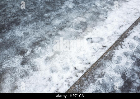 Winter urban road. Ice and wet snow lay on the roadside Stock Photo