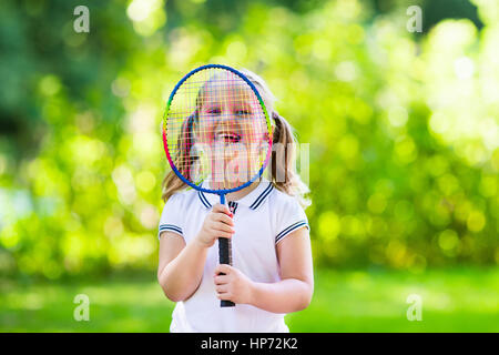 Active preschool girl playing badminton in outdoor court in summer. Kids play tennis. School sports for children. Racquet and shuttlecock sport for ch Stock Photo