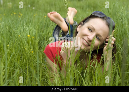 Model released, Junge Frau, 30, liegt entspannt in der Fruehlingswiese - woman relaxing in spring meadow Stock Photo