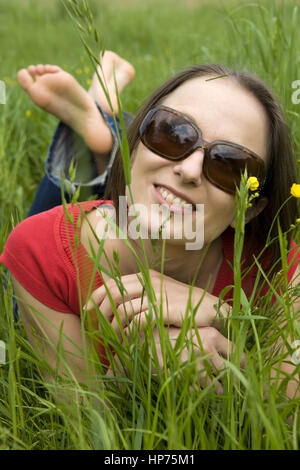 Model released, Junge Frau, 30, liegt entspannt in der Fruehlingswiese - woman relaxing in spring meadow Stock Photo
