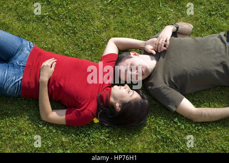 Model released, Liebespaar liegt in der Wiese - love couple lying in meadow Stock Photo
