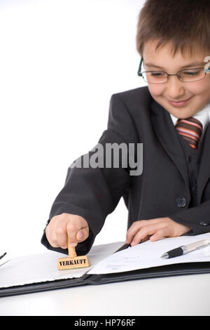 Model released, 'Kleiner Geschaeftsmann mit Stempel ''Verkauft'' im Buero - little businessman stamping in office' Stock Photo