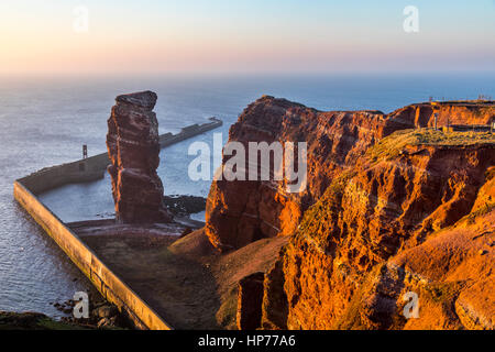 The red steep coast line of Helgoland, an German Island in the North Sea, rock needle called Lange Anna, the landmark of the island, Stock Photo