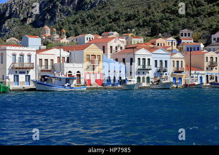 View of the east side of the main harbor with fishing boats moored to the quay and neoclassical restored houses on the hillside-Agios Georgos tou Hora Stock Photo