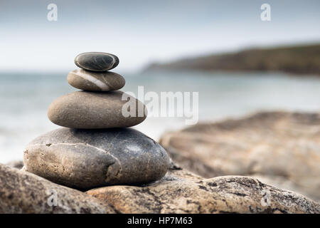 Fishguard, Wales - Large pebbles stacked into a tall pile on the beach Stock Photo