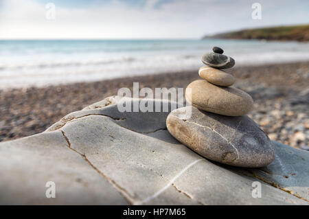 Fishguard, Wales - Large pebbles stacked into a tall pile on the beach Stock Photo