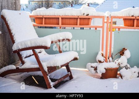 Snow covereddeck deck chair stands in winter on a snowy balcony Stock Photo