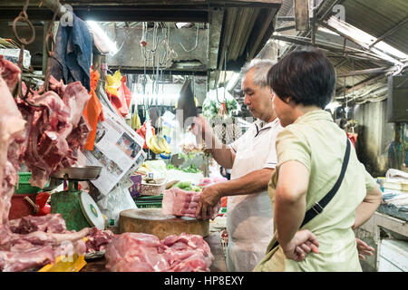 A butcher chops meat for a customer at his stall in Chinatown, Kuala Lumpur, Malaysia Stock Photo