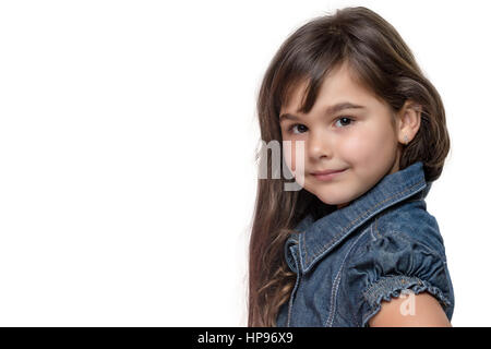 Portrait of long haired brunette little girl isolated on the white background. Girl is standing sideways and is looking at the camera. Free place for  Stock Photo