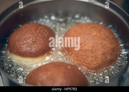 Three homemade doughnuts frying in hot oil Stock Photo