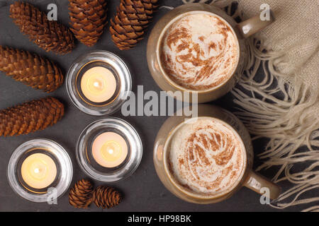 Mugs of creamy mocha (coffee and chocolate) served on slate by candle light in a cosy English home Stock Photo