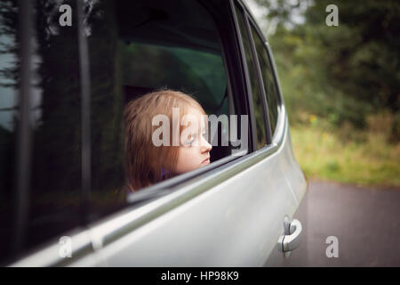 Girl looking out of open car window Stock Photo