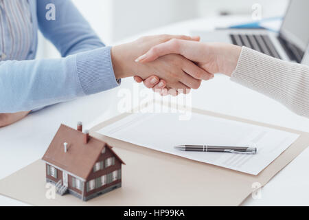 Real estate broker and customer shaking hands after signing a contract: real estate, home loan and insurance concept Stock Photo