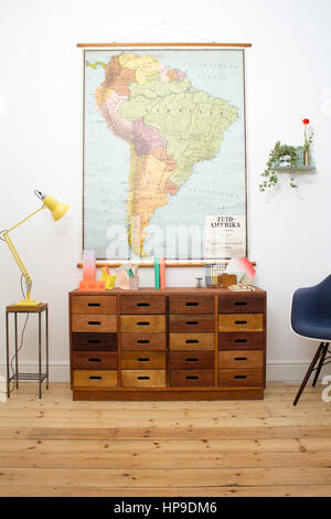 A Mid-Century modern chest of drawers in a home office with an antique map hanging above Stock Photo