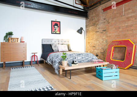 A bedroom in a loft style apartment with exposed brick and midcentury furniture Stock Photo
