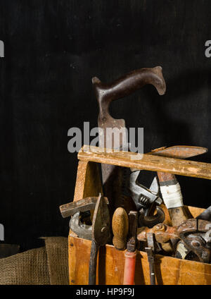 Old used tools in the toolbox. Dark background. spot lighting. Wooden box. Repair work. Stock Photo