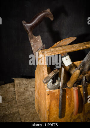 Old used tools in the toolbox. Dark background. spot lighting. Wooden box. Repair work. Stock Photo