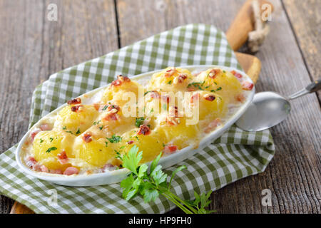 Hearty potato dumplings baked with cheese and bacon, freshly served from the oven Stock Photo