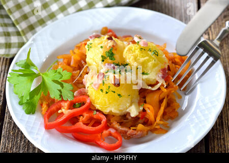 Hearty potato dumplings gratin with cheese and bacon served on paprika cabbage Stock Photo