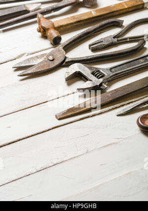 Many old rusty tools scattered on the wooden tstolu. View from above. Space for text. Stock Photo