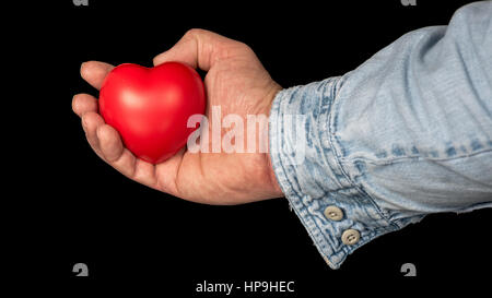 Mans hand holds a stress ball that is in the shapes of a heart Stock Photo