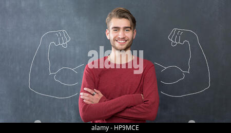 Young man against the background of depicted muscles on chalkboard Stock Photo