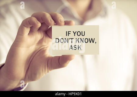 Closeup on businessman holding a card with text IF YOU DONT KNOW, ASK, business concept image with soft focus background and vintage tone Stock Photo