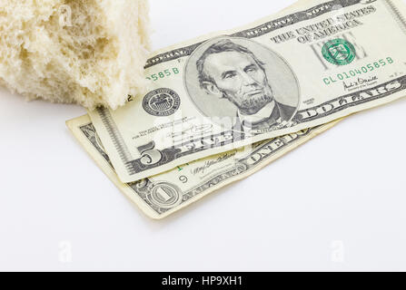 Piece of bread and dollar bills on white background - Conceptual image depicting povery in America Stock Photo