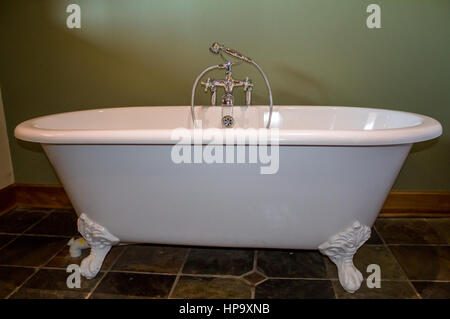 Vintage type footed white bath tub in olive green bathroom with slate tile floor Stock Photo