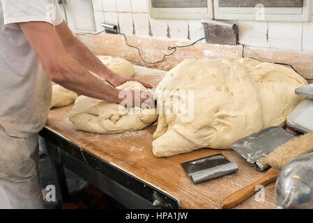 Male baker hands kneading the dough fro bread production in bakery Stock Photo