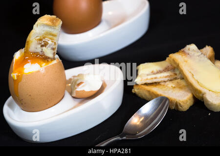 A close up of soft boiled hens egg with a toasted soldier dipped in the yolk. Stock Photo
