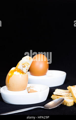 A close up of soft boiled hens egg with a toasted soldier dipped in the yolk. Stock Photo