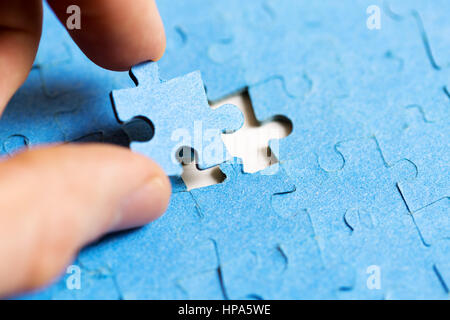 mission complete concept - hand placing last piece of jigsaw puzzle Stock Photo