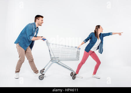 woman pointing way and while pulling shopping cart with man Stock Photo