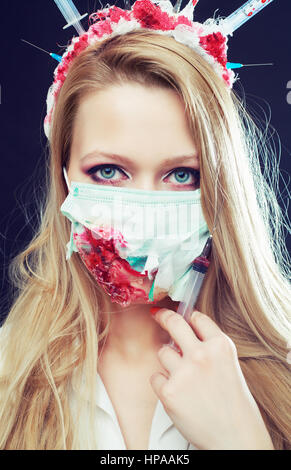 Halloween costume of a crazy nurse with crown made of syringes and a syringe in the hand Stock Photo