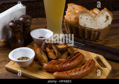 hot sausages serving on wooden board with white beer in restaurant Stock Photo