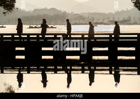 Five tourists in silhouette cross a bridge at Hangzhou's West Lake scenic area Stock Photo
