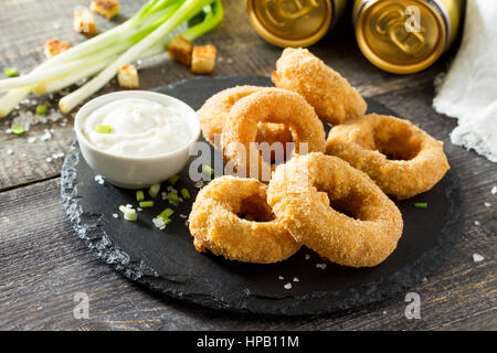 Onion rings fried with cheese on slate board. Snack food to beer on a wooden table. Stock Photo