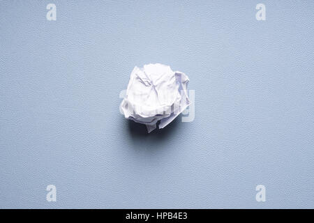 crumpled-up ball of paper on blue background Stock Photo