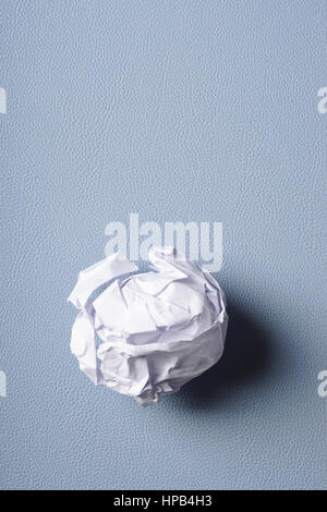 crumpled-up ball of paper on blue background Stock Photo