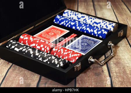 Chips cards and dice in black suitcase close up. Poker set in suitcase on wooden table. Poker play concept Stock Photo