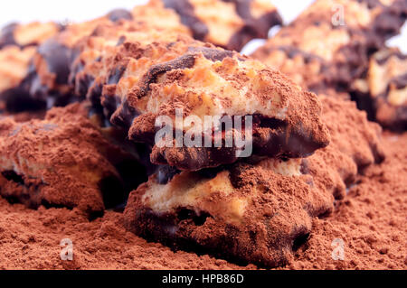 Pile of shortbread cookies with jam and chocolate icing on the scattered cocoa powder on white background. Stock Photo