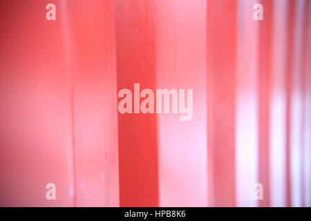 Red ribbed metal close up. Transportation container wall closeup. Red shiny background. Soft focus on red ribbed wall. Stock Photo