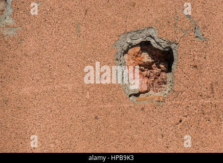 Orange concrete wall with a trace of a bullet shot Stock Photo