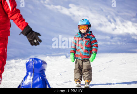 Young skier looking at ski instructor while sliding down mountain slope. Ski lesson in alpine school. Stock Photo