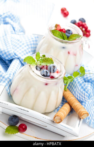 Fresh yogurt with berries and wafer rolls. On white table. Stock Photo
