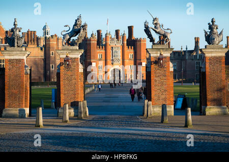 Hampton Court Palace: Main Entrance gate with gate posts and drive leading to the Central Gatehouse, West Front, of the Palace; blue sky & sun. UK. Stock Photo