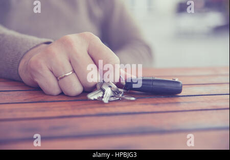 Hands of man holding the car keys with black wallet on wooden table Stock Photo