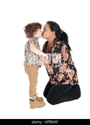 A Filipino nanny kneeling on the floor and kissing the little boy, standing in front of her, isolated for white background. Stock Photo