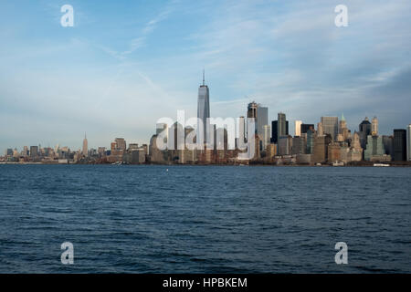 Famous New York City skyline and New York Harbor as seen from a boat.  Blue skies and cirrus clouds over New York's Financial district.  Sunny day loo